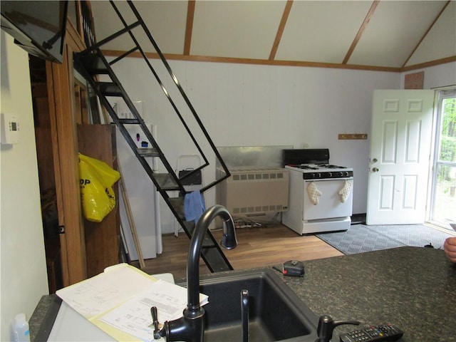 kitchen featuring lofted ceiling, white gas stove, and hardwood / wood-style flooring