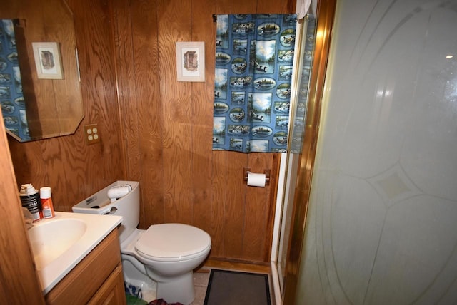 bathroom featuring vanity, toilet, and wood walls