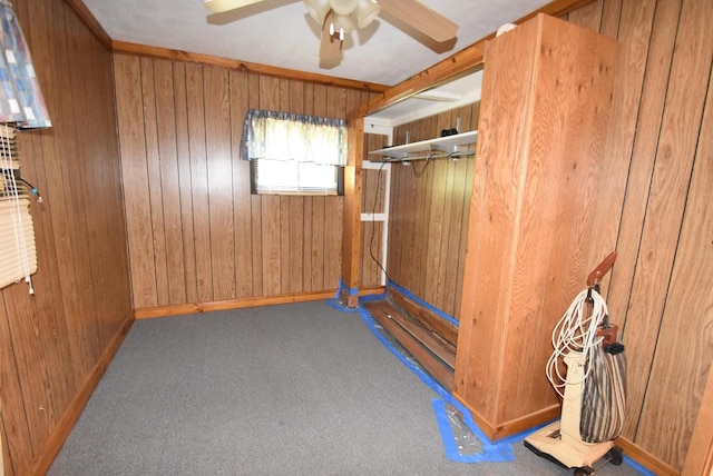 interior space featuring carpet flooring, ceiling fan, and wood walls