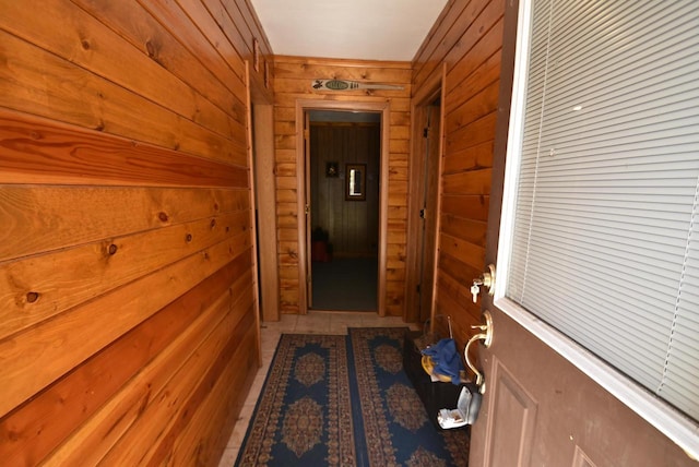 doorway with tile patterned floors and wood walls