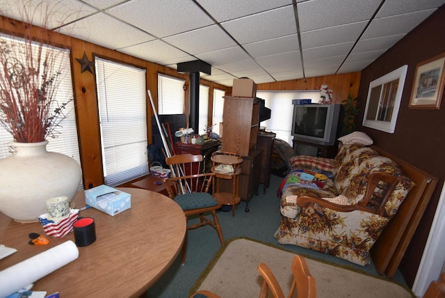 living room featuring a paneled ceiling, carpet flooring, and wood walls