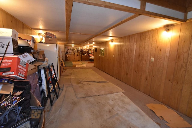 basement featuring white fridge and wooden walls