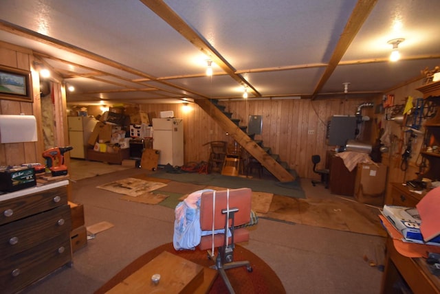 basement featuring wood walls and white fridge