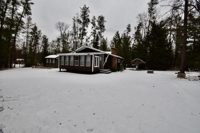 snow covered house featuring a sunroom