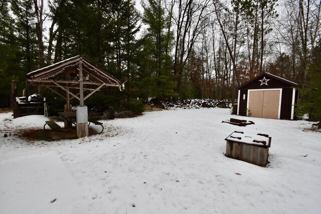 yard layered in snow with a gazebo and a shed