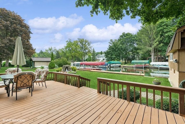 wooden deck featuring a boat dock, outdoor dining area, and a lawn