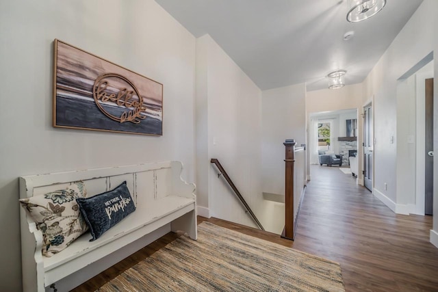 hall featuring an upstairs landing, baseboards, and wood finished floors