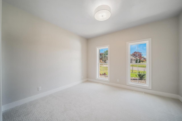 empty room featuring light carpet and baseboards