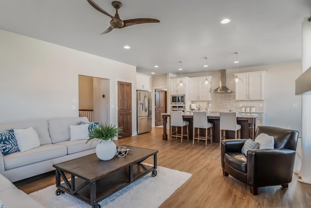 living room with a ceiling fan, recessed lighting, and light wood-style floors