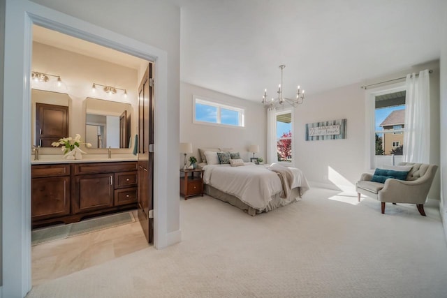 bedroom featuring a notable chandelier, light colored carpet, ensuite bathroom, and a sink