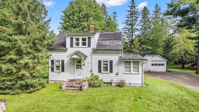 view of front of property with an outbuilding, a garage, and a front lawn