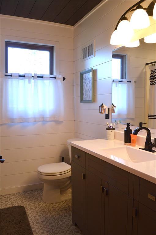 bathroom with vanity, toilet, ornamental molding, and walk in shower