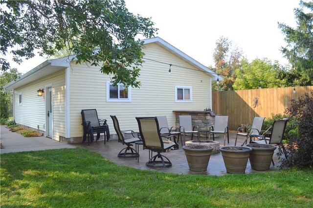 back of house with an outdoor fire pit, a yard, and a patio