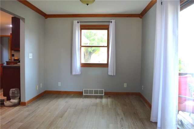 unfurnished room featuring ornamental molding and light hardwood / wood-style flooring