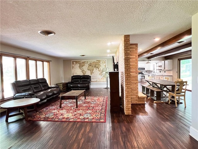 living room featuring a textured ceiling, plenty of natural light, and dark hardwood / wood-style flooring