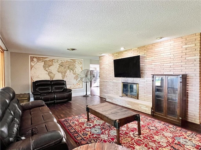 living room featuring a fireplace, dark hardwood / wood-style flooring, and a textured ceiling