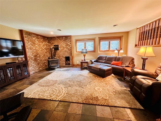 living room featuring stone finish flooring, brick wall, and a wood stove