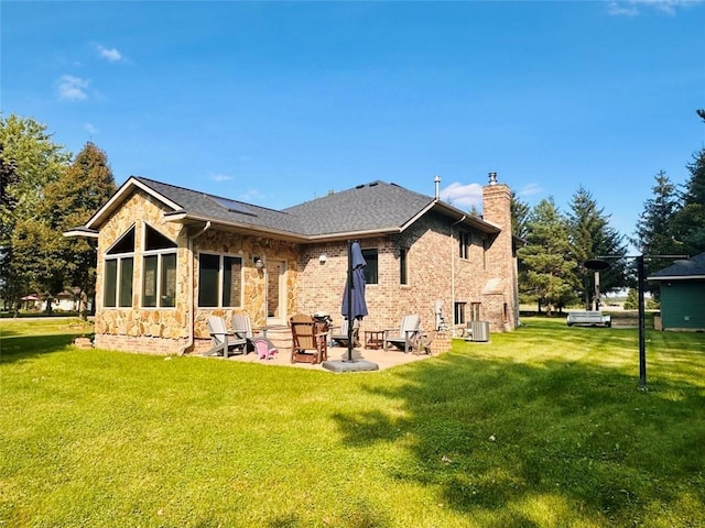 back of house featuring a patio, a chimney, central air condition unit, a lawn, and brick siding