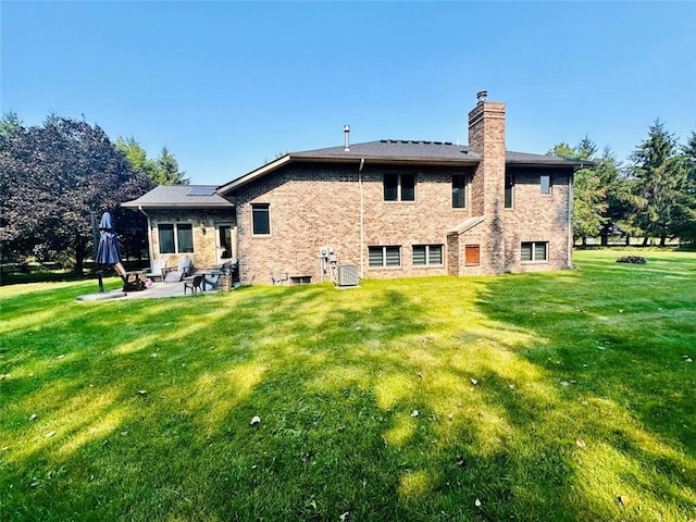 rear view of house with a patio, central AC unit, a lawn, and a chimney