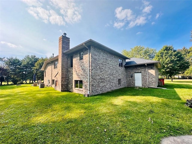 view of side of home with brick siding, a lawn, cooling unit, and a chimney