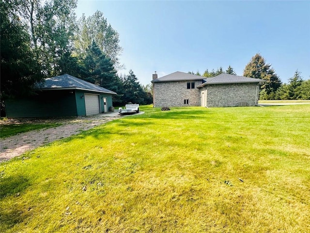 view of yard with an outbuilding, a detached garage, and driveway