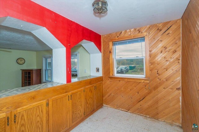 6275 S County Rd A, Superior, WI 54880 - kitchen with arched walkways, wood walls, brown cabinets, and light floors