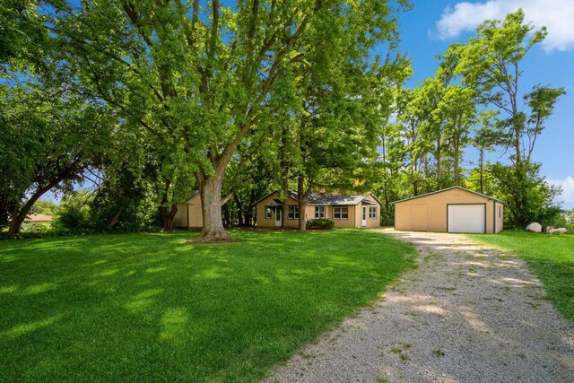 view of front of house featuring an outdoor structure, a garage, and a front lawn