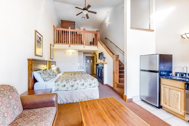 carpeted bedroom with ceiling fan, sink, stainless steel fridge, and high vaulted ceiling