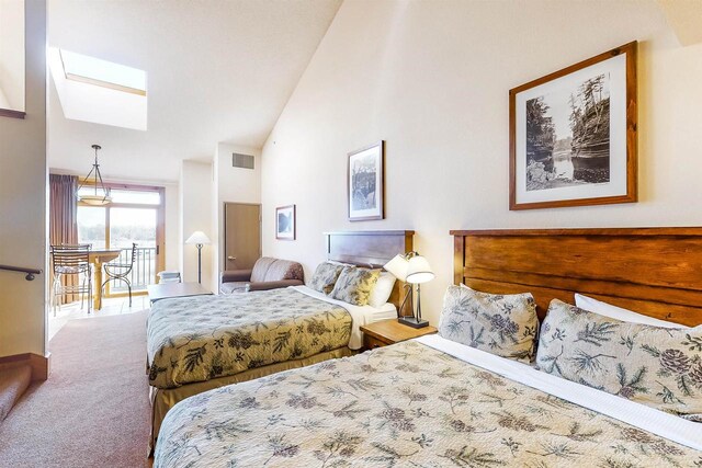 bedroom featuring high vaulted ceiling, a skylight, and carpet