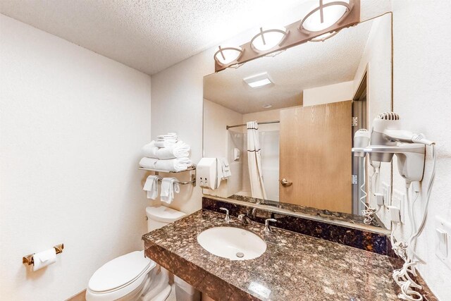 bathroom featuring a textured ceiling, toilet, curtained shower, and sink