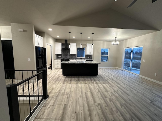 kitchen featuring light wood finished floors, wall chimney exhaust hood, a kitchen island, white cabinetry, and backsplash