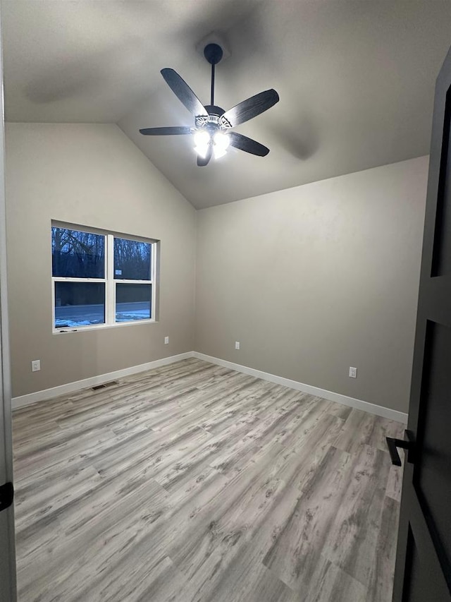 unfurnished room with lofted ceiling, a ceiling fan, visible vents, baseboards, and light wood finished floors