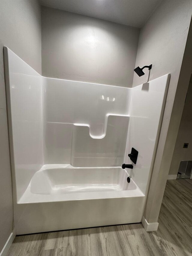 bathroom featuring  shower combination and wood finished floors