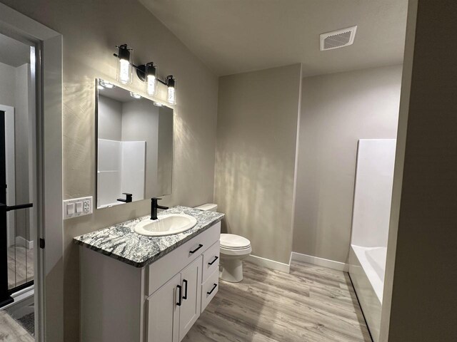 full bathroom featuring visible vents, toilet, vanity, wood finished floors, and baseboards