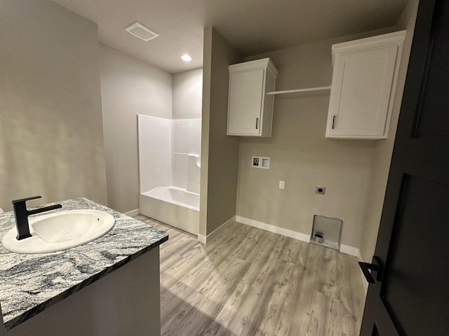 bathroom with recessed lighting, wood finished floors, bathing tub / shower combination, vanity, and baseboards