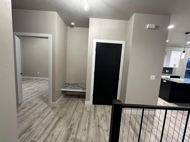 corridor featuring light wood-type flooring and baseboards