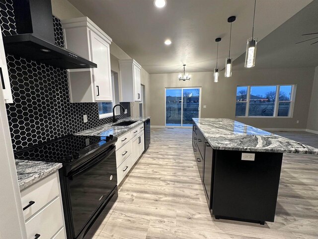 kitchen featuring a kitchen island, a sink, wall chimney range hood, black appliances, and light wood finished floors