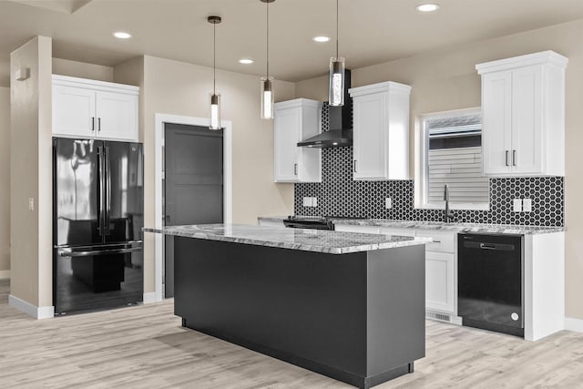 kitchen with white cabinets, light wood-style flooring, wall chimney range hood, a center island, and black appliances