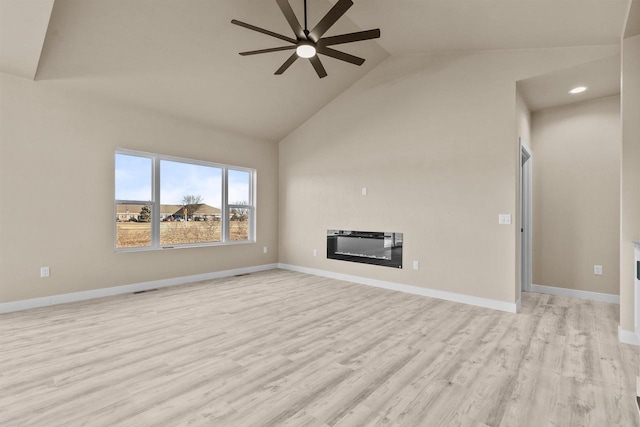 unfurnished living room featuring light wood-style flooring, a ceiling fan, a glass covered fireplace, high vaulted ceiling, and baseboards