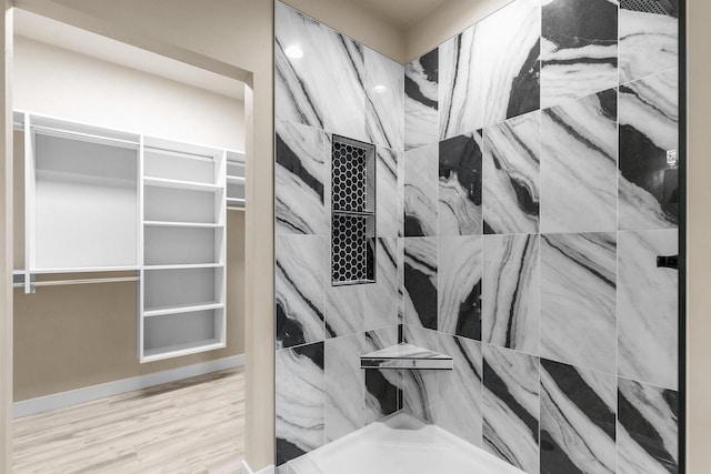 interior details with a tile shower and wood finished floors