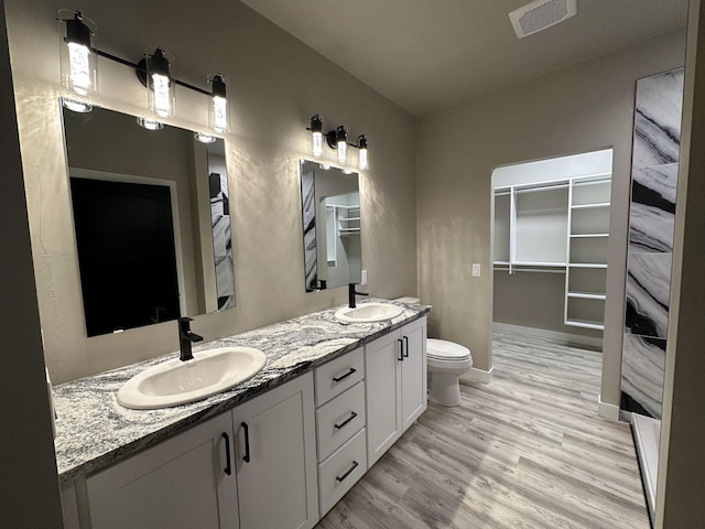 bathroom with double vanity, visible vents, a sink, and wood finished floors