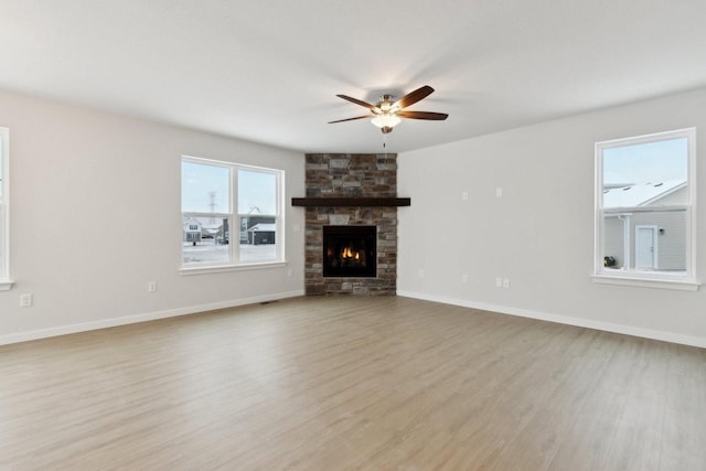 unfurnished living room featuring a fireplace, a wealth of natural light, light hardwood / wood-style floors, and ceiling fan