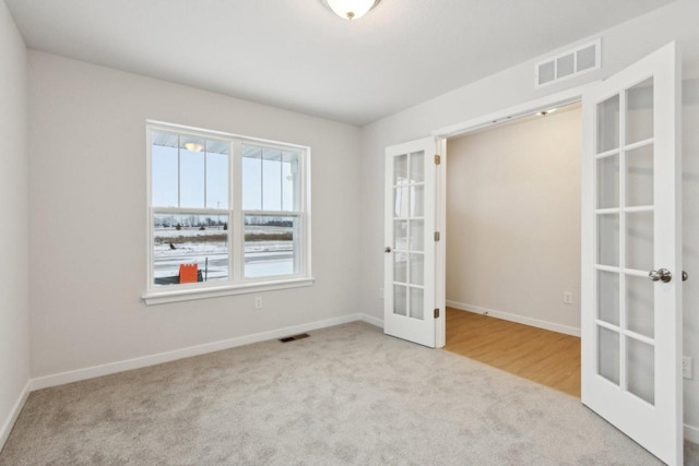 carpeted spare room featuring french doors