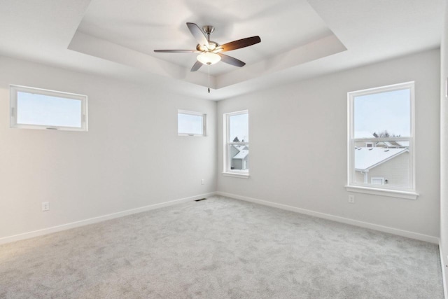 carpeted empty room featuring a raised ceiling and ceiling fan