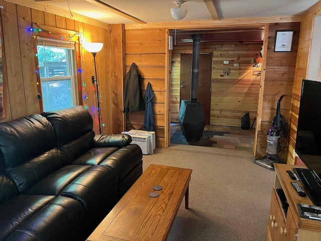 living room with wooden walls, a wood stove, and carpet flooring