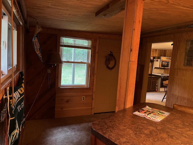 entrance foyer featuring light carpet, wooden walls, and wooden ceiling