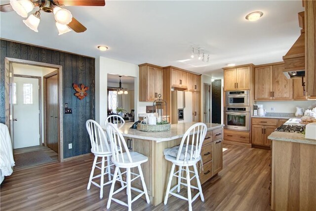 kitchen with a kitchen breakfast bar, dark hardwood / wood-style flooring, light stone counters, kitchen peninsula, and custom range hood