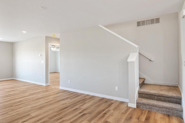 staircase featuring visible vents, a ceiling fan, baseboards, and wood finished floors