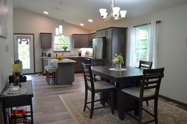 dining space featuring an inviting chandelier, lofted ceiling, dark hardwood / wood-style floors, and plenty of natural light