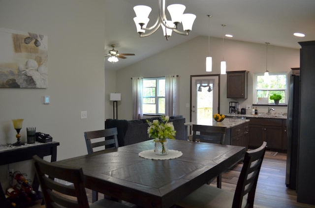 dining room featuring wood-type flooring, ceiling fan with notable chandelier, vaulted ceiling, and a wealth of natural light